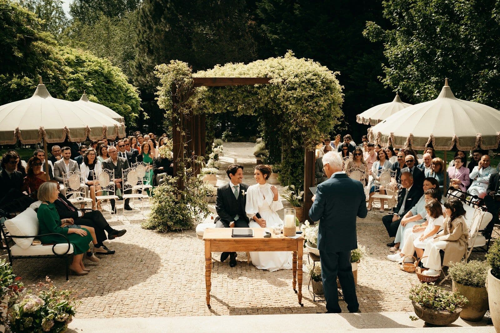 Ceremonia de boda al aire libre con invitados bajo sombrillas