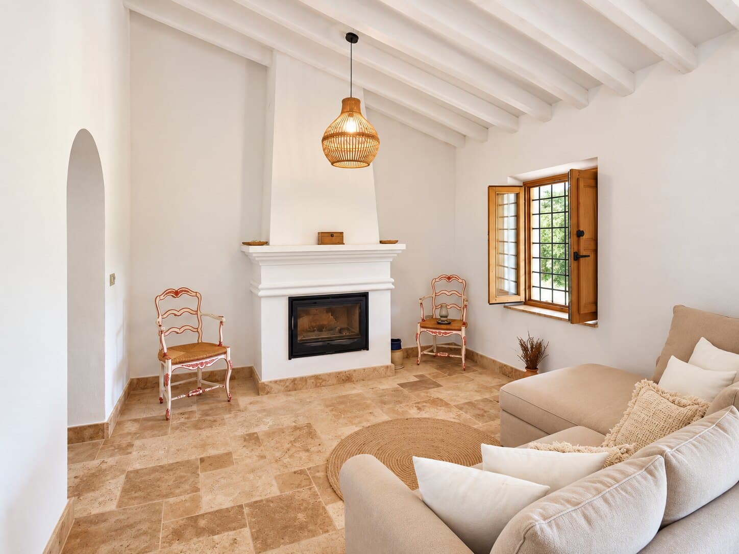 Sala con chimenea blanca, sillones y techo de vigas