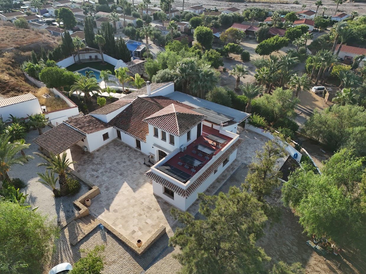 Vista aérea del cortijo, con la piscina, el patio empedrado y la vegetación que lo rodea